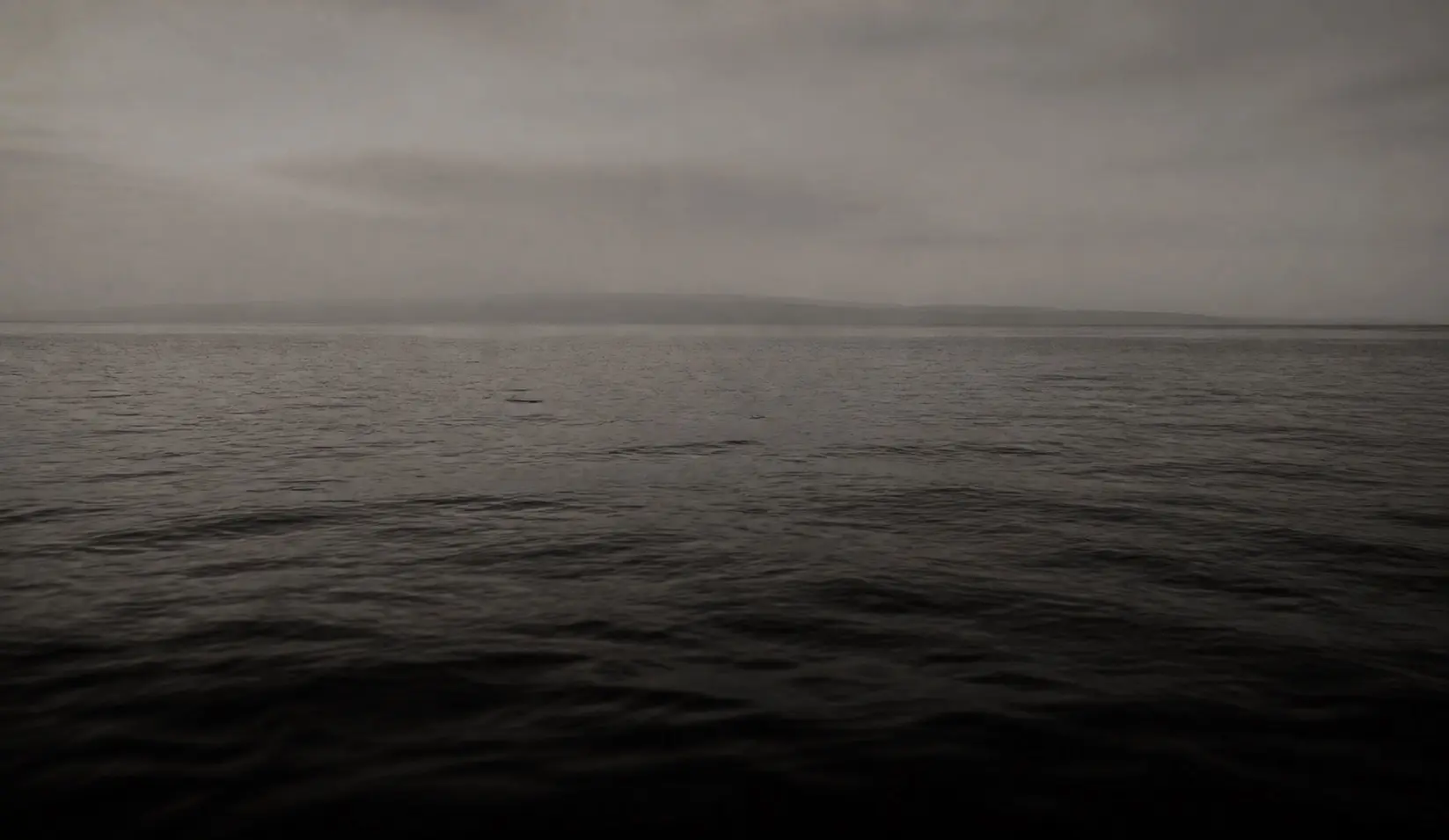 Dark ocean waters beneath a misty coastal horizon